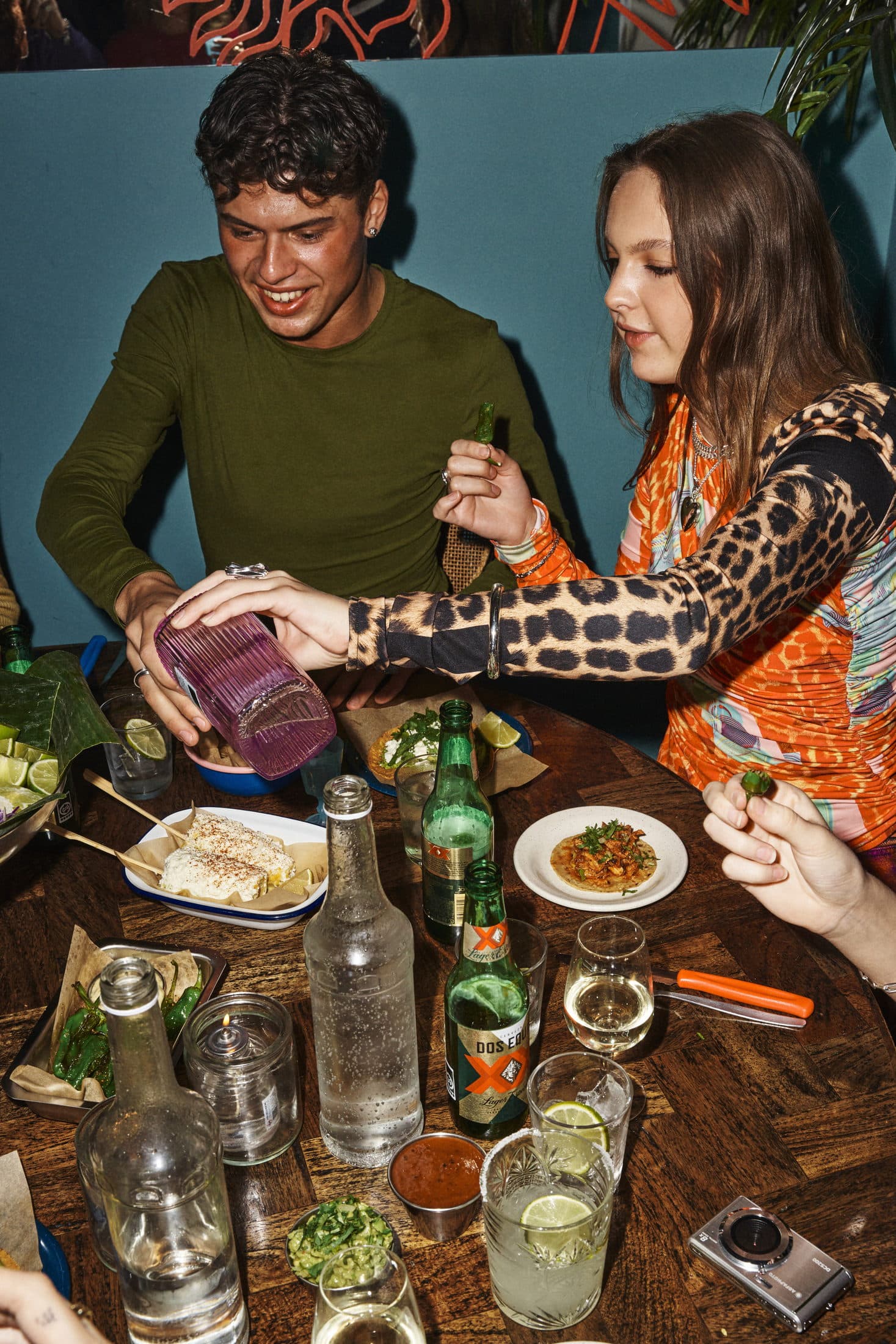 Friends sharing tacos and drinks at a long table at Mæxico